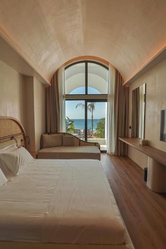 a hotel room with a bed and a large window at Hotel Camelot By Artur in Ksamil
