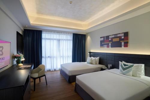 a hotel room with two beds and a desk at Bespoke Hotel Puchong in Puchong