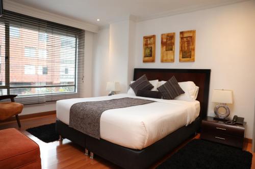 a bedroom with a large bed and a large window at Hotel Suites 108 in Bogotá