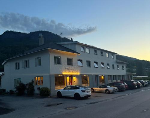 a large white building with cars parked in front of it at Bringenatten Hotell Nesbyen in Nesbyen