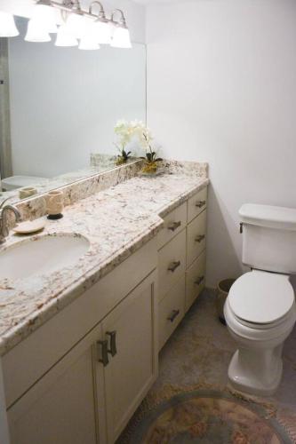 a bathroom with a sink and a toilet and a mirror at Jupiter Bay Beach Condo in Jupiter