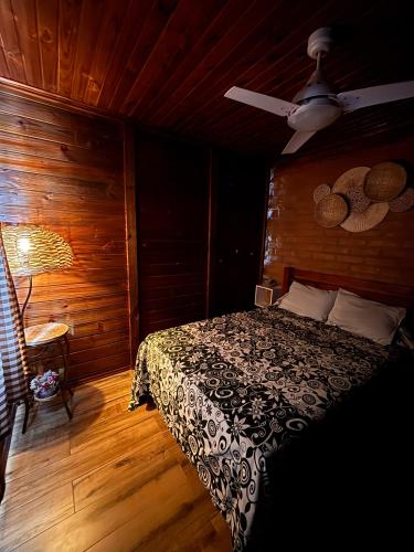 a bedroom with a bed in a wooden room at Recanto Sol Maior - Casa Lírio in Sapucaí-Mirim