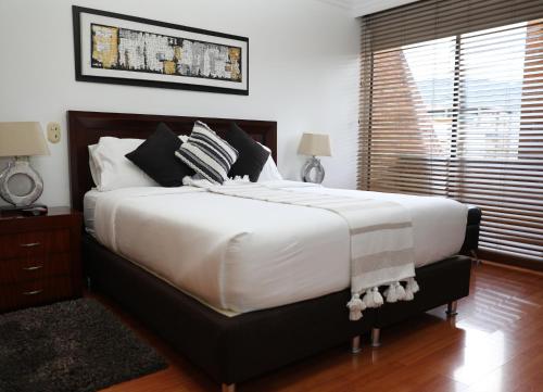 a bedroom with a large bed with white sheets and pillows at Hotel Suites 108 in Bogotá