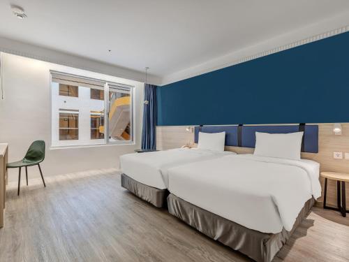 a large bed in a room with a blue wall at CHECK inn Select Taipei Nangang in Taipei
