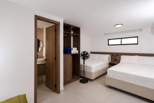 a hotel room with two beds and a fan at Hotel Balcones del Estadio in Medellín