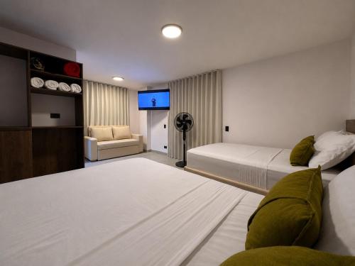 a bedroom with two beds and a flat screen tv at Hotel Balcones del Estadio in Medellín