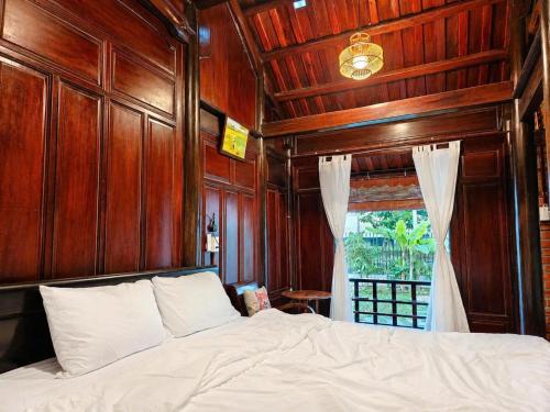 a bedroom with a bed with wooden walls and a window at La Belle Saison Homestay Huế in Hue