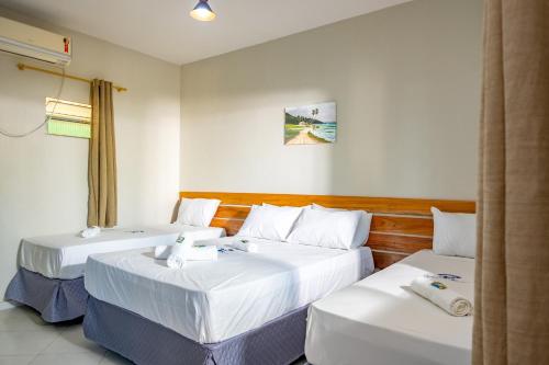 two beds in a hotel room with white sheets at Pousada Bela Vista in Conde