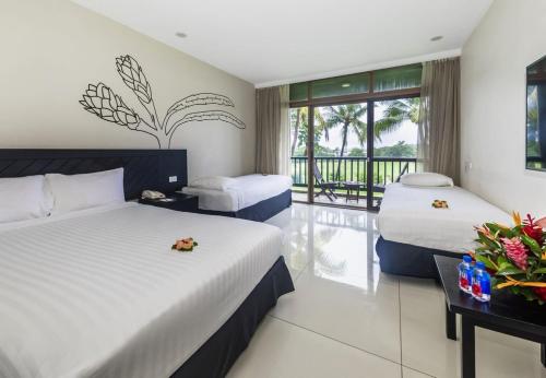 a hotel room with two beds and a balcony at Tanoa International Hotel in Nadi