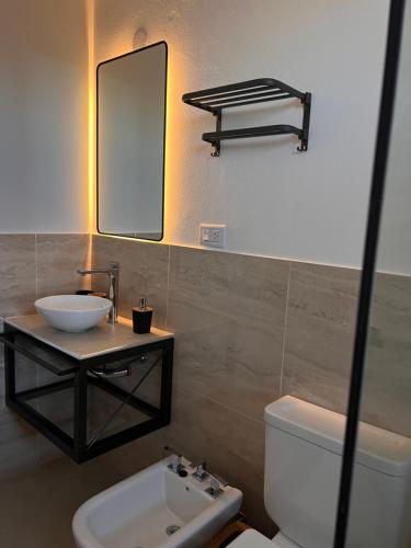 a bathroom with a sink and a mirror and a toilet at Monteolivos Home & Suites in El Rincón