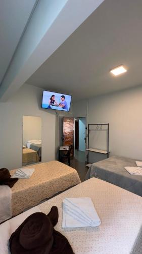 a room with three beds and a flat screen tv at Recanto Pau Brasil in Sete Lagoas