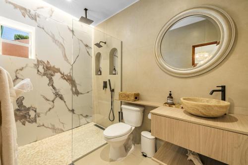a bathroom with a sink and a toilet and a mirror at NEW RENOVATION - Beachside Two-Bedroom Suite in Savaneta