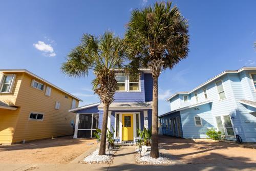 two palm trees in front of a house at Salty Waves | Beach Cottage, Walk to Beach, Pool, Fenced Yard & Grill in Port Aransas