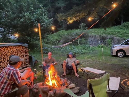a group of people sitting around a fire at KOMINKA guest house in Omachi