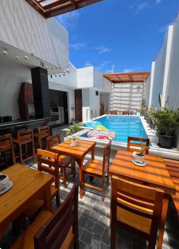 a patio with wooden tables and chairs and a swimming pool at Mihahi Beach Mancora in Máncora