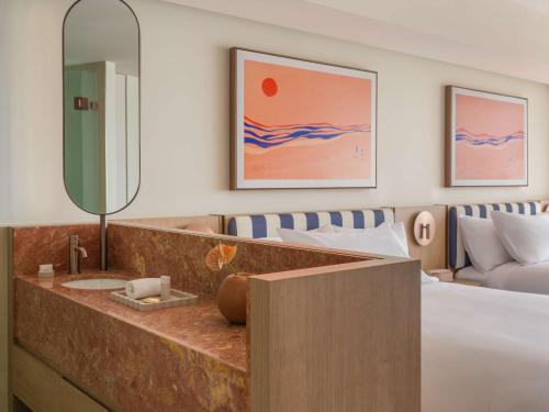 a bedroom with a bed and a sink and a mirror at Avani Mooloolaba Beach Hotel in Mooloolaba