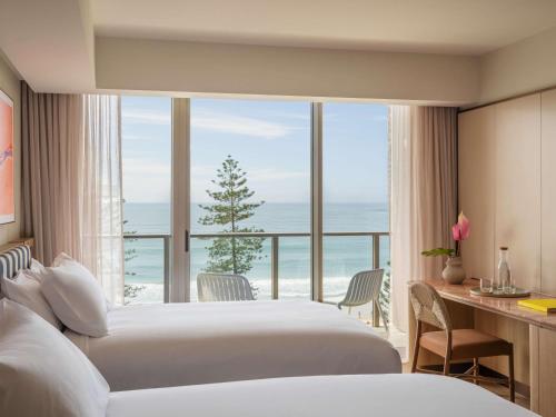 two beds in a hotel room with a view of the ocean at Avani Mooloolaba Beach Hotel in Mooloolaba