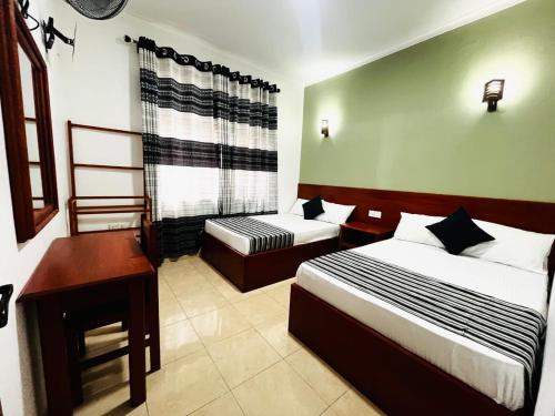 a hotel room with two beds and a desk at Moonstone Holiday Cottages in Badulla
