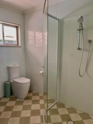 a bathroom with a toilet and a glass shower at Cedarvale Cottage in Boambee