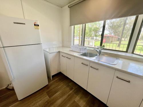 a kitchen with a white refrigerator and a sink at Young Tourist Park in Young