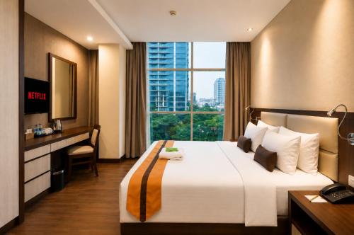 a hotel room with a bed with a desk and a window at Oria Hotel Jakarta in Jakarta