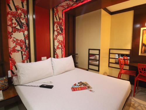 a bedroom with a white bed with a phone on it at Hotel Sogo Edsa Cubao in Manila
