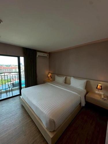 a bedroom with a large bed and a large window at L Hotel in Ban Si Than