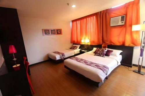 a hotel room with two beds and an orange curtain at Cityinn Hotel in Zamboanga