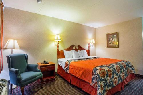 a hotel room with a bed and a chair at Rodeway Inn & Suites in Tupelo