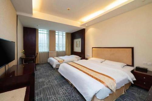 a hotel room with two beds and a flat screen tv at Wanyi Hotel in Dongguan