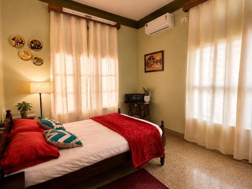 a bedroom with a bed with red sheets and a window at The Timeless Mysuru bungalow in Mysore