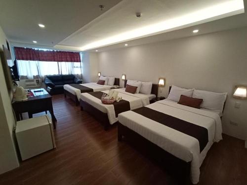 a hotel room with two beds and a couch at Hotel Asuncion in Laoag