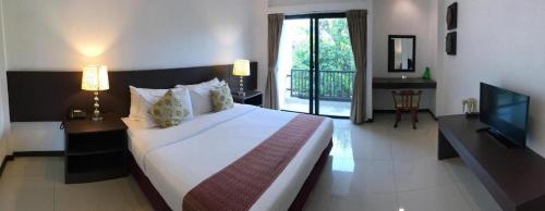 a bedroom with a large bed and a television at Baan Nan Hotel in Nan
