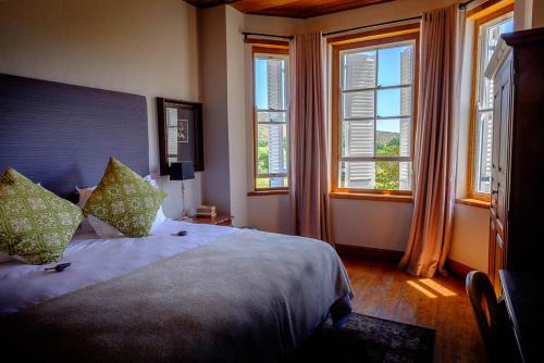 a bedroom with a large bed with windows at Vrisch Gewagt Boutique Self-Catering Olive Farm in Prince Albert