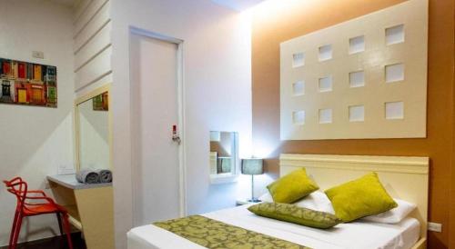 a bedroom with a bed with yellow pillows at Hotel Monde in Dagupan