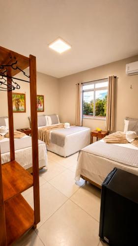 a hotel room with three beds and a television at Pousada Coco Babaçu in Viçosa do Ceará