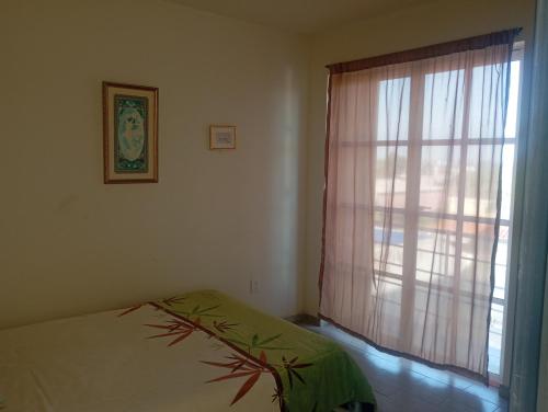 ein Schlafzimmer mit einem Bett und einem Fenster mit einem Vorhang in der Unterkunft Casa LM in San Miguel de Allende