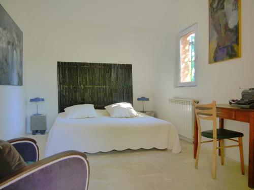 a bedroom with a white bed and a table and a desk at L'Ostal du Pic St Loup in Saint-Jean-de-Cuculles