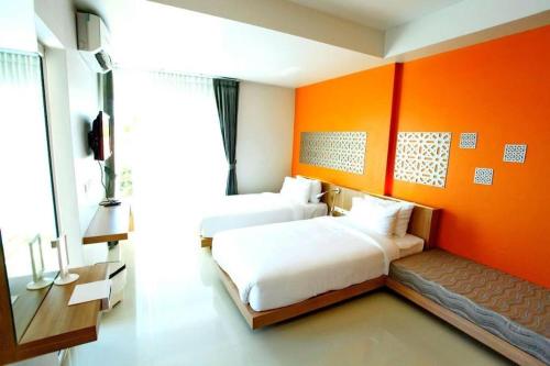 two beds in a room with an orange wall at Tonkok Hotel in Ban Fang Min