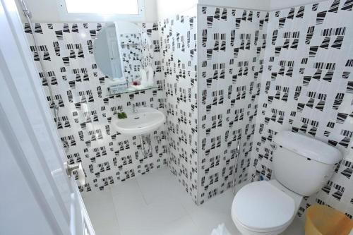 a white bathroom with a toilet and a sink at Tonkok Hotel in Ban Fang Min