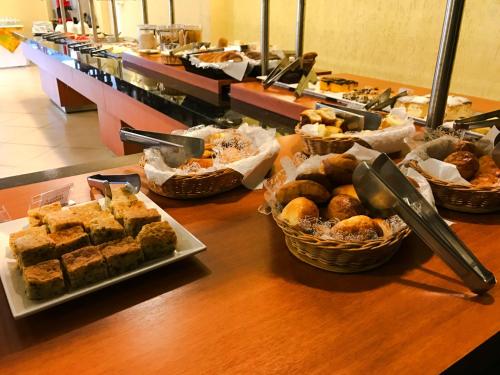 a table with several baskets of pastries and other foods at Rede Andrade Mercado Hotel in Curitiba