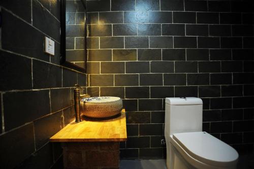 a black tiled bathroom with a toilet and a sink at Shu Hostel in Guiyang