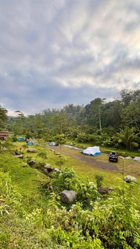 a group of tents in a field next to a river at camp asri in Bukittinggi