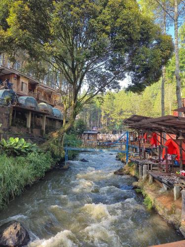 a river with a group of buildings and a bridge at camp asri in Bukittinggi