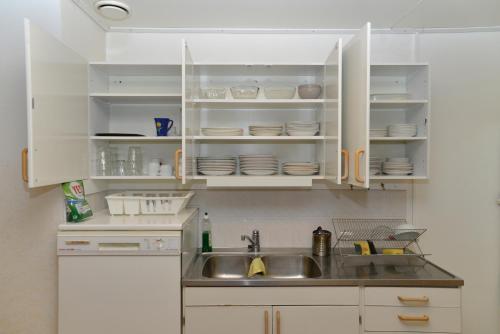 a kitchen with white cabinets and a sink at Hostel Finnmyrten in Juoksengi