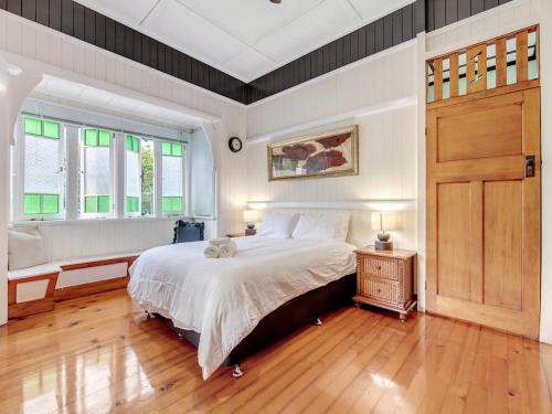 a bedroom with a large bed and two windows at Historic Character-filled Jade Cottage in Coalfalls