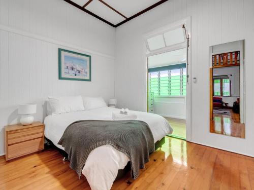 a white bedroom with a large bed and a window at Historic Character-filled Jade Cottage in Coalfalls