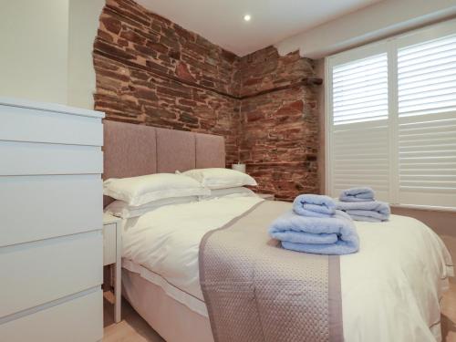 a bedroom with a bed and a brick wall at Rock House in Tintagel