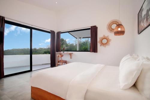 a bedroom with a white bed and a large window at Villa Panoramic in Nusa Penida