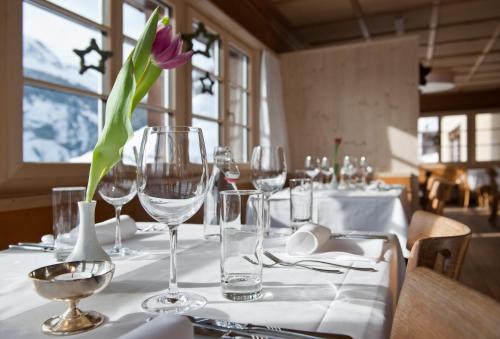 a table with glasses and a vase with a flower on it at Hotel Restaurant Capricorns in Wergenstein